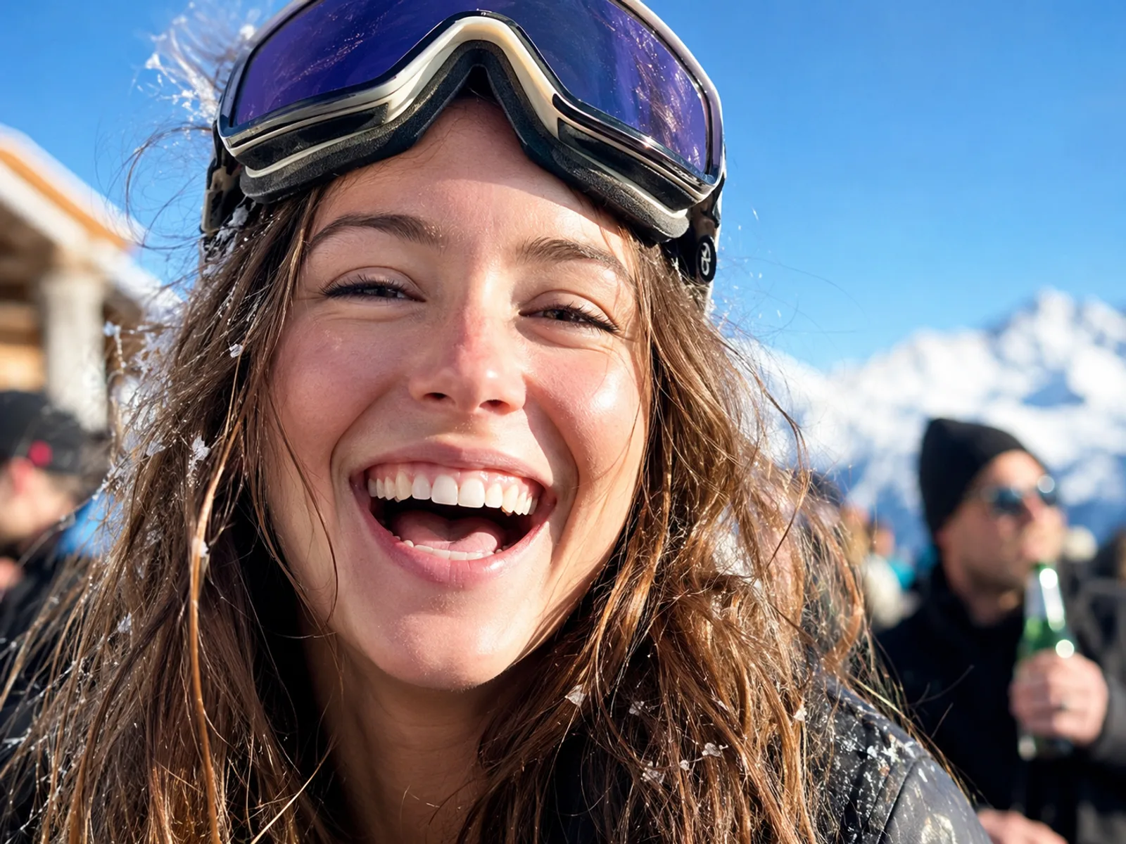 Nahaufnahme einer lachenden Frau beim Après-Ski mit Skibrille