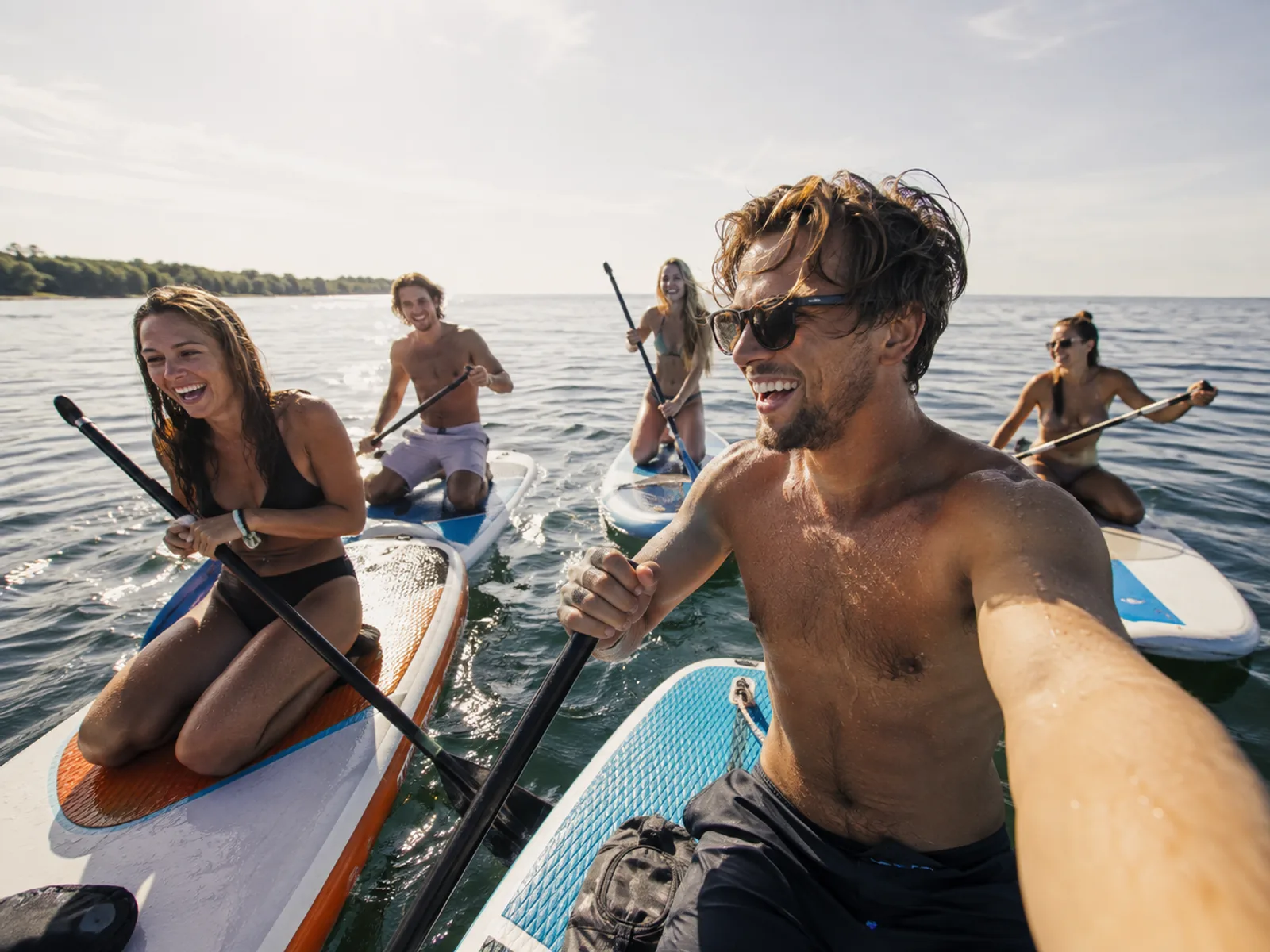 Junge Männer und Frauen fahren gemeinsam Stand-Up-Paddle