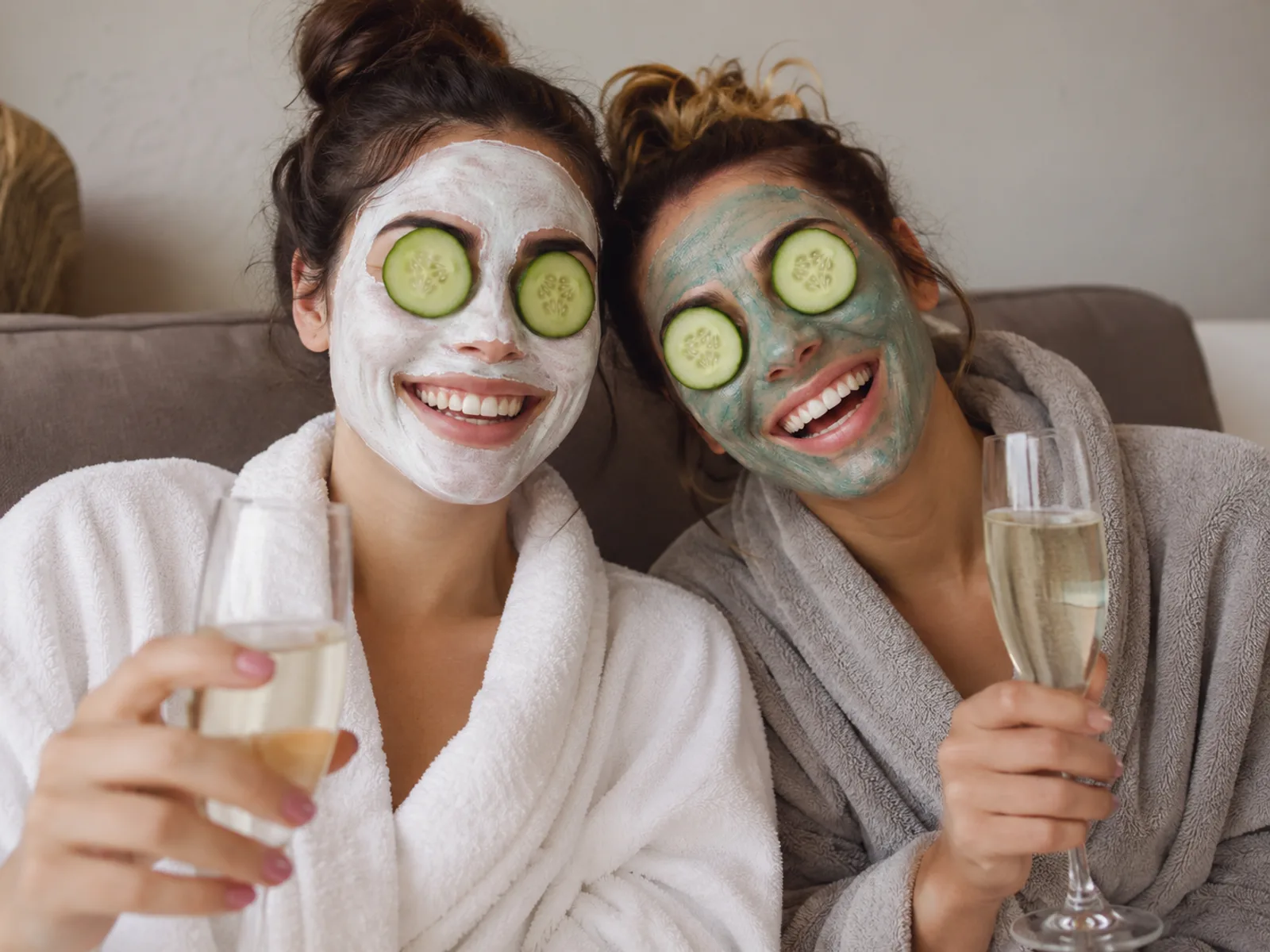 Nahaufnahme zweier Freundinnen mit Gesichtsmasken und Sektgläsern